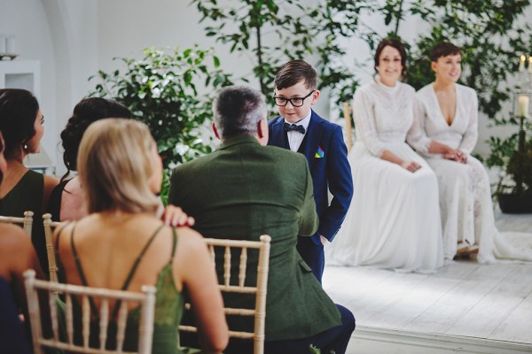 Little boy standing in front of man and brides at top of alter setting