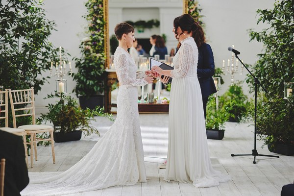 Brides stand in front of guests during wedding ceremony with yellow ribbon