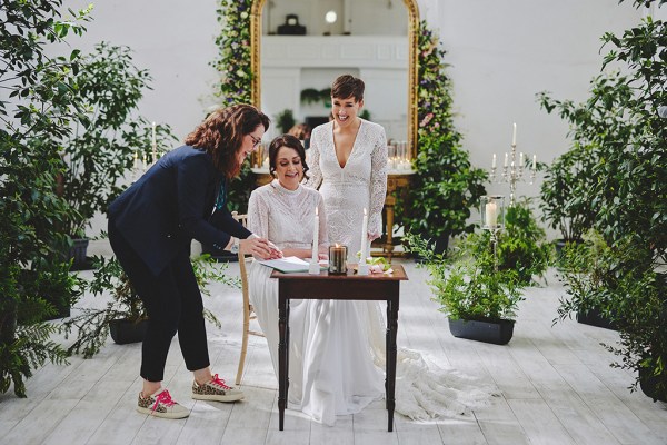 Brides and celebrant signing marriage certificate