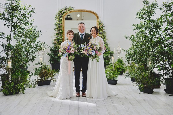 Father and two brides pose for a photo