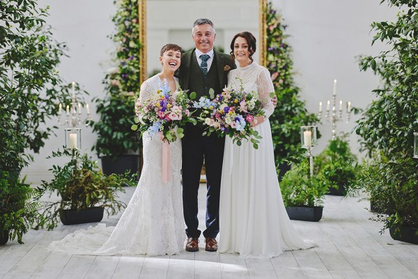 Father and two brides pose for a photo