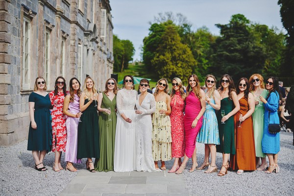 Family and friends portrait in a row outside wedding venue