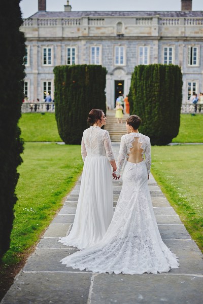 Brides walk from behind towards wedding venue along pathway