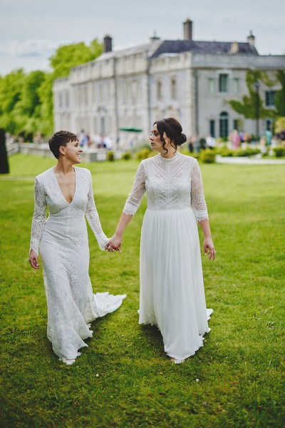 Brides walking on grass in forest garden setting venue in background