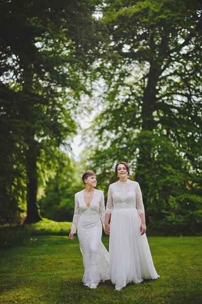 Brides walking on grass in forest garden setting