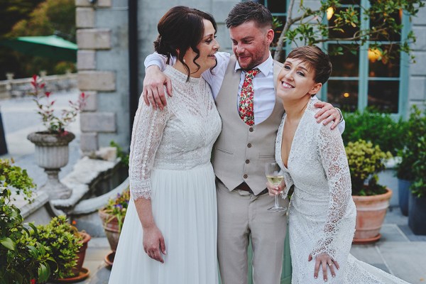 Brides pose with man in suit