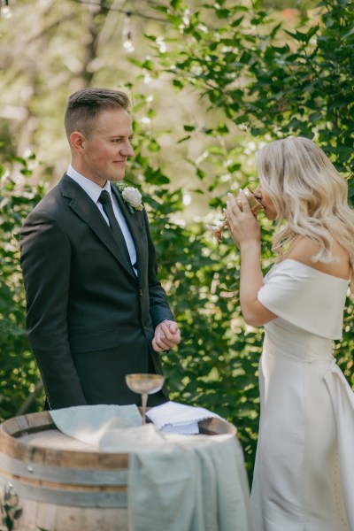 bride and groom hold glasses of wine and drink