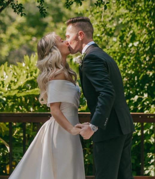 bride and groom kiss at the alter trees in the background