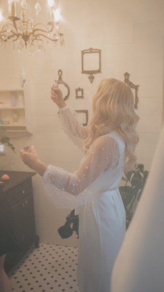 misty photo of bride spraying perfume on her