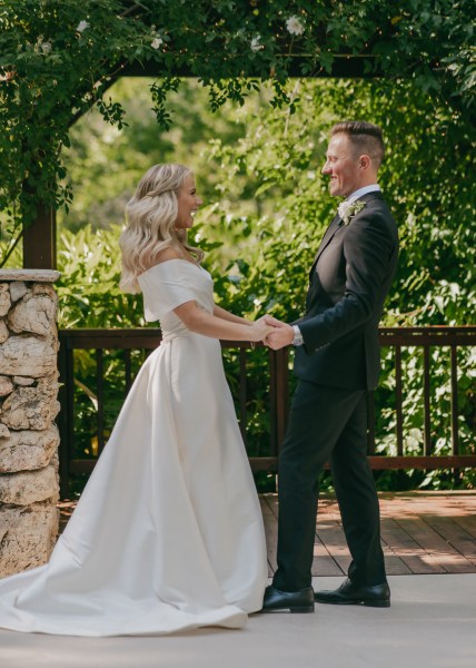 bride and groom hold hands at the alter trees in the background