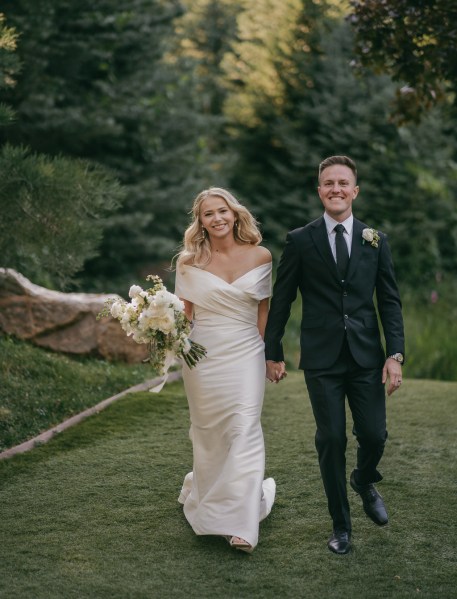 bride and groom all smiles as they walk on the green grass holding hands