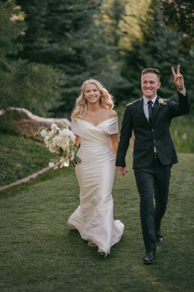 bride and groom all smiles as they walk on the green grass holding hands