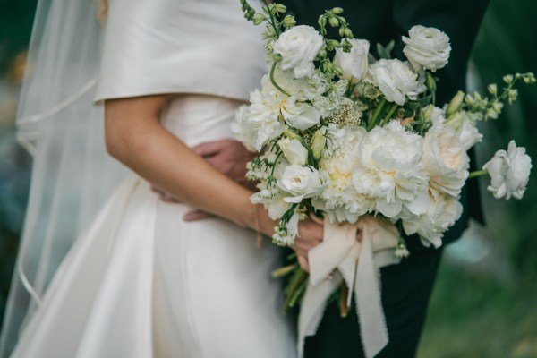 close up of brides white rose bouquet veil and dress