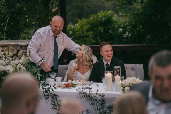 bride and groom along with father smile at the dining room table