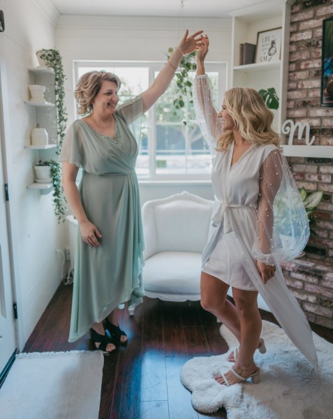 bride and her mother get ready together hands/arms in the air