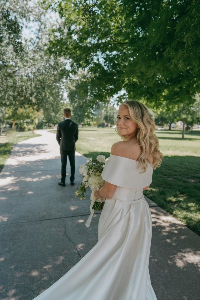 groom has his back to blonde bride who is walking towards him