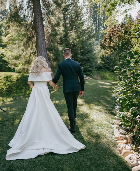 bride and groom from behind as they walk on the grass