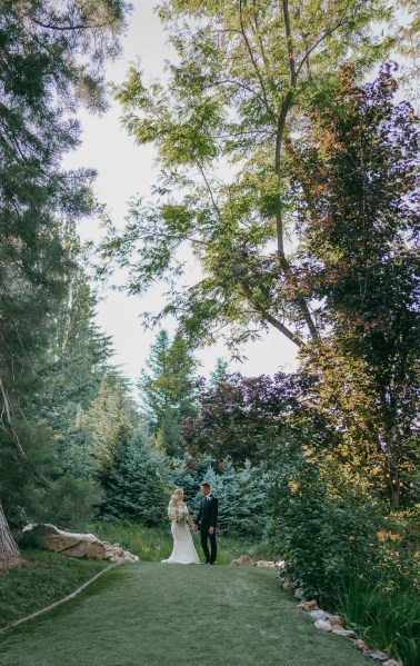 bride and groom from afar in garden surrounded by trees