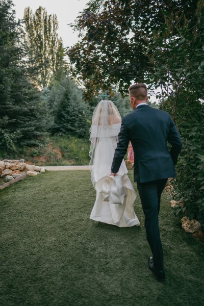 bride and groom from behind as they walk on the grass