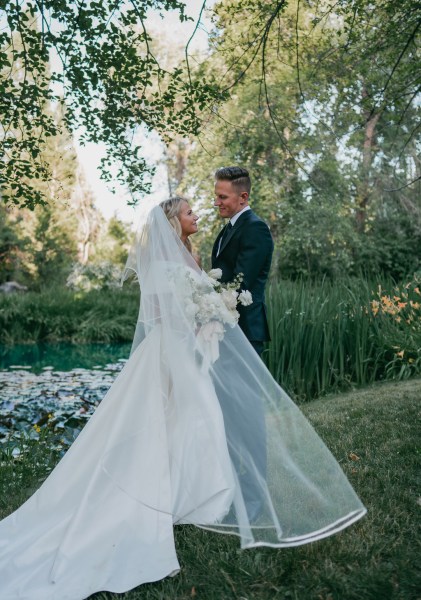 bride and groom look at each other in the garden