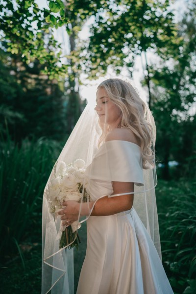 bride and veil detail she's holding bouquet in garden