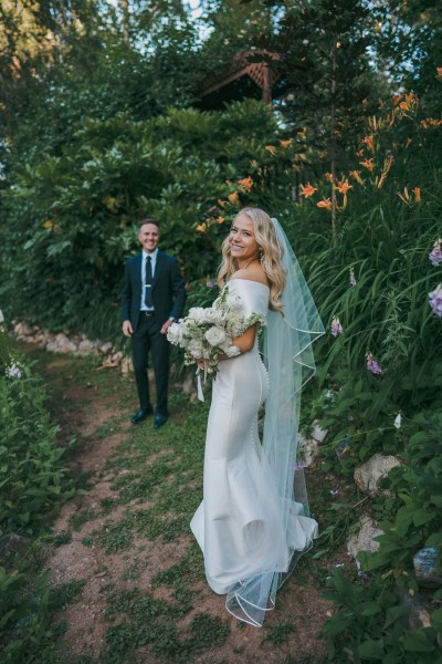 bride looks over her shoulder as groom approaches