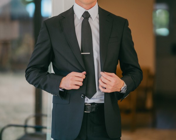 groom shows off his suit as he's ready for wedding