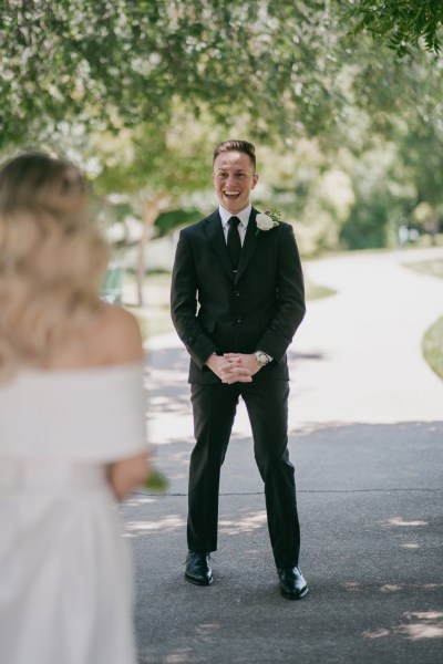 bride approaches groom in forest