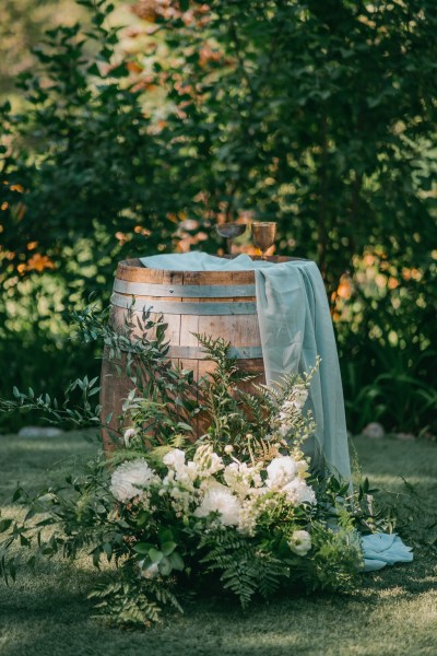 barrel covered in blue cloth and white rose flowers at the bottom