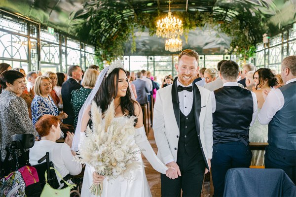 photo of bride and groom holding hands exiting ceremony venue