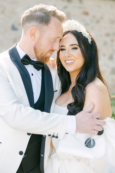 Bride and groom embracing and smiling outside