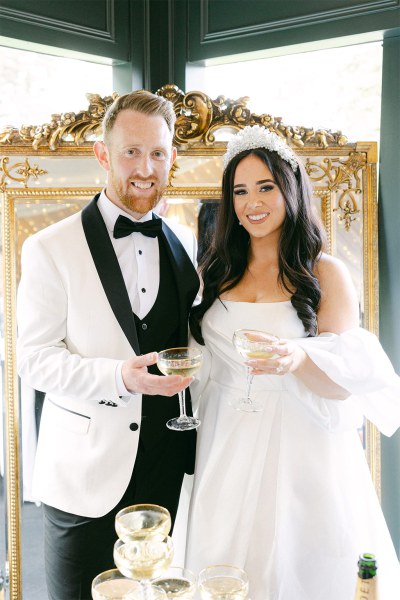 Bride and groom hokd glasses of champagne and smile