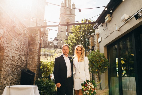 bride and groom outside ceremony office black gates sunshine bouquet in shot