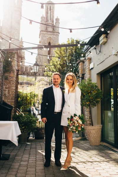 bride and groom outside ceremony office black gates sunshine bouquet in shot