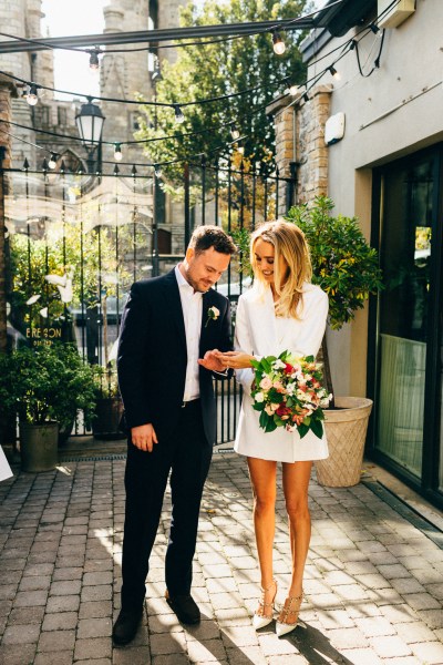 bride and groom outside ceremony office black gates sunshine bouquet in shot