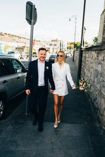 bride and groom walking along pathway hand in hand