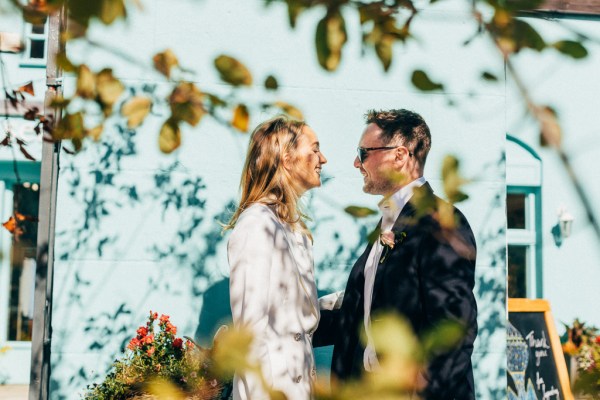 bride and groom stand facing each other smiling in garden forest setting