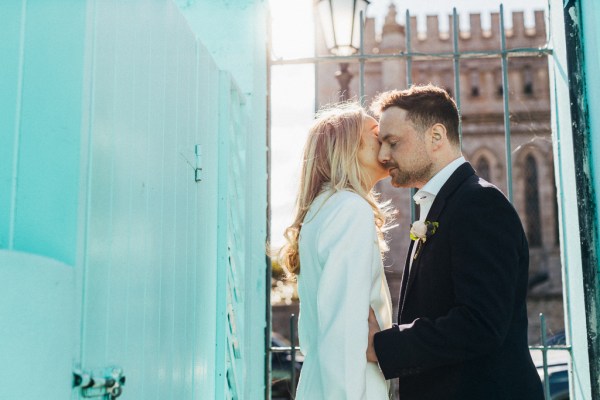 blue wall bride and groom go in for a kiss hugging embracing