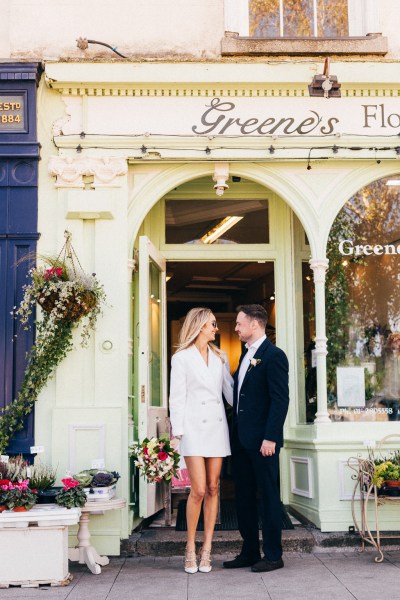 bride and groom under door archway she wears sunglasses outside of wedding venue