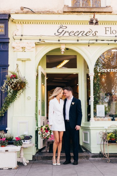 bride and groom under door archway she wears sunglasses outside of wedding venue they touch foreheads