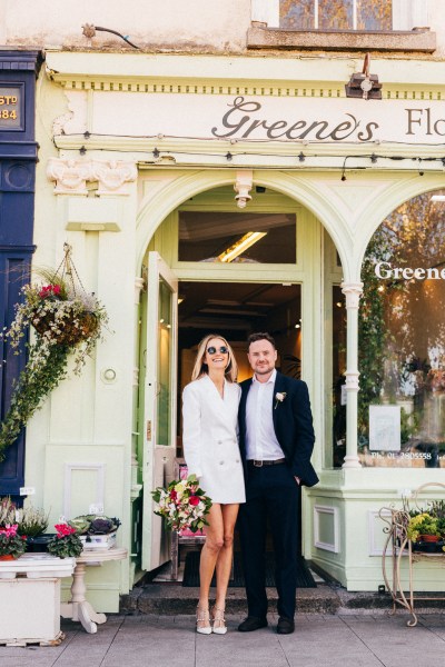 bride and groom under door archway she wears sunglasses outside of wedding venue