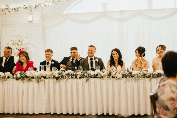 bride groom groomsmen and bridesmaids sit at the dining room table together