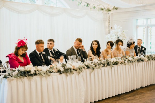 groom bride bridesmaids and groomsmen sit at the dining room table together