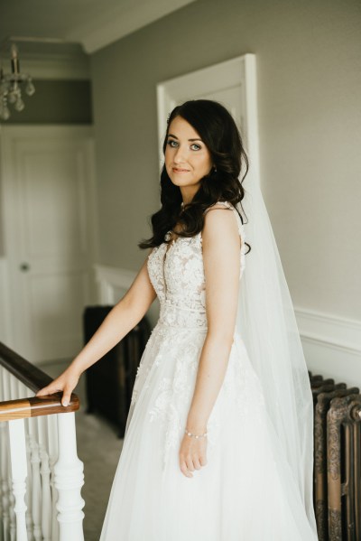 Brides stands at top of staircase in house