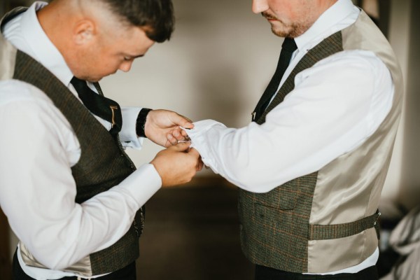 groom and groomsman getting ready together fixing up cufflinks