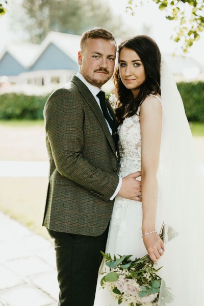 bride and groom stand in the garden together hugging