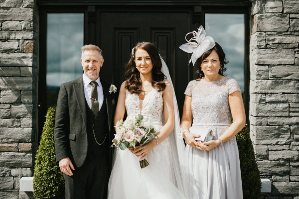 bride father and mother pose outside of house