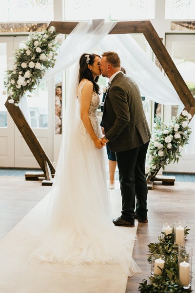 bride and groom kiss at the alter