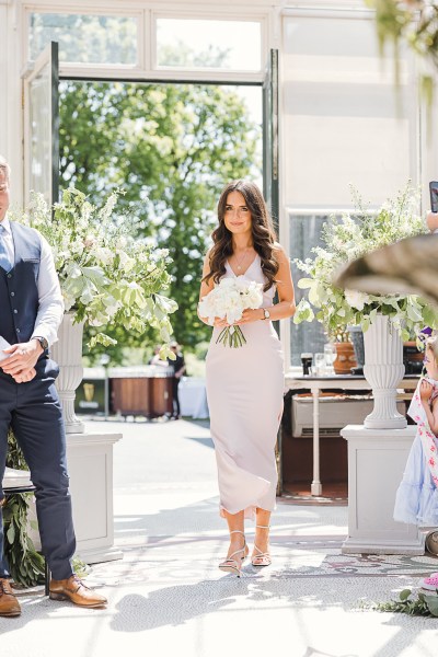 bridesmaid in white dress walks down the aisle