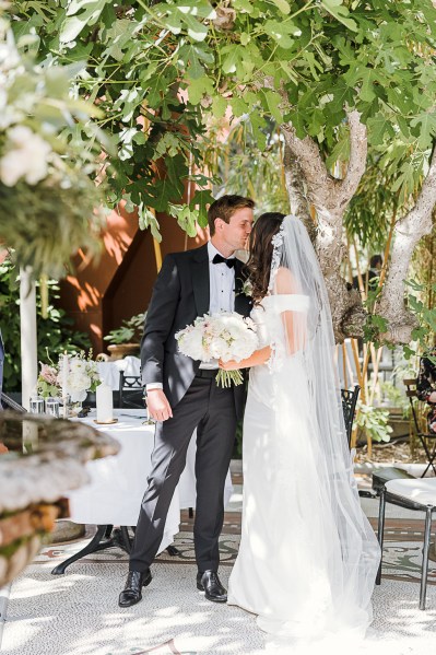 bride and groom kiss she holds bouquet